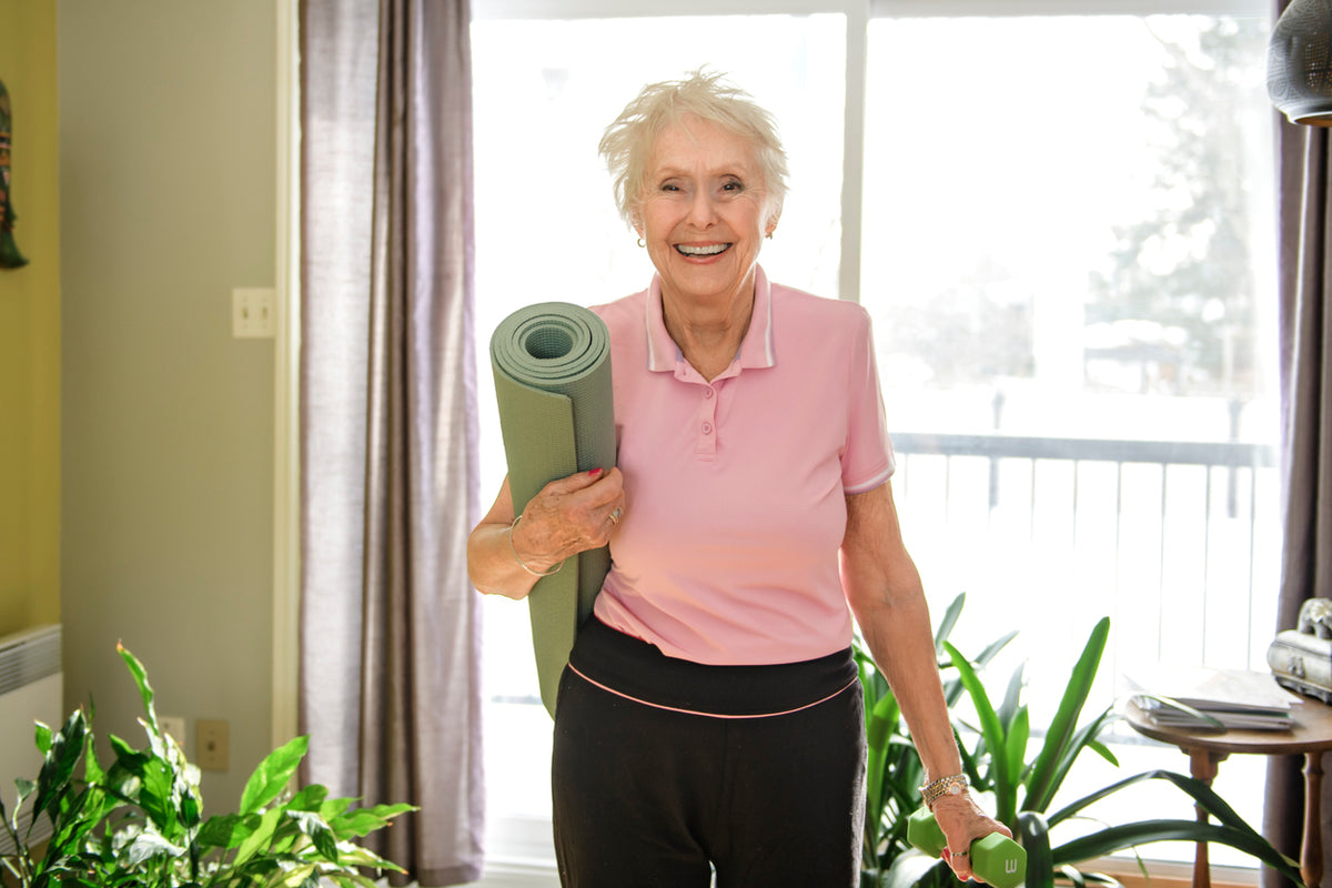 Ältere Dame mit einer Yoga Matte unter dem Arm